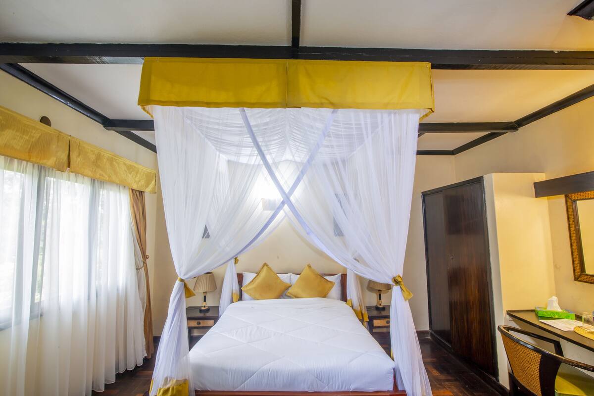 A bed with a canopy, a bedside table, a chair, and curtains.