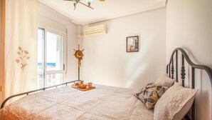Un dormitorio con cama, ventana, aire acondicionado y vista al mar.