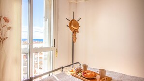 Una cama con una bandeja de comida, una taza y un sombrero sobre un atril.