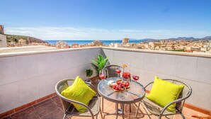 Una terraza en la azotea con una mesa para dos, dos sillas y vistas a la ciudad y al mar.