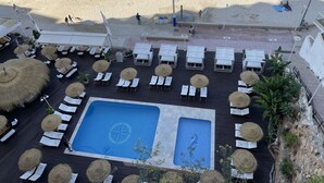 Vista aérea de um resort com área de piscina, praia e espreguiçadeiras.