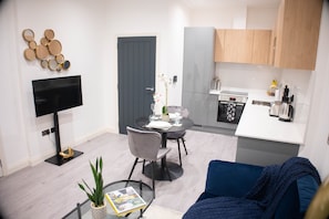 Um espaço compacto com área de refeições, cozinha compacta e sala de estar com sofá azul.