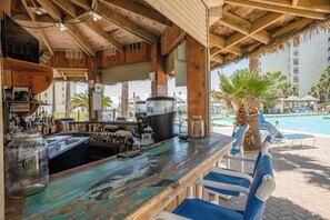 Relax by the pool with a refreshing drink at our resort's bar, featuring a rustic bar counter and stunning views.