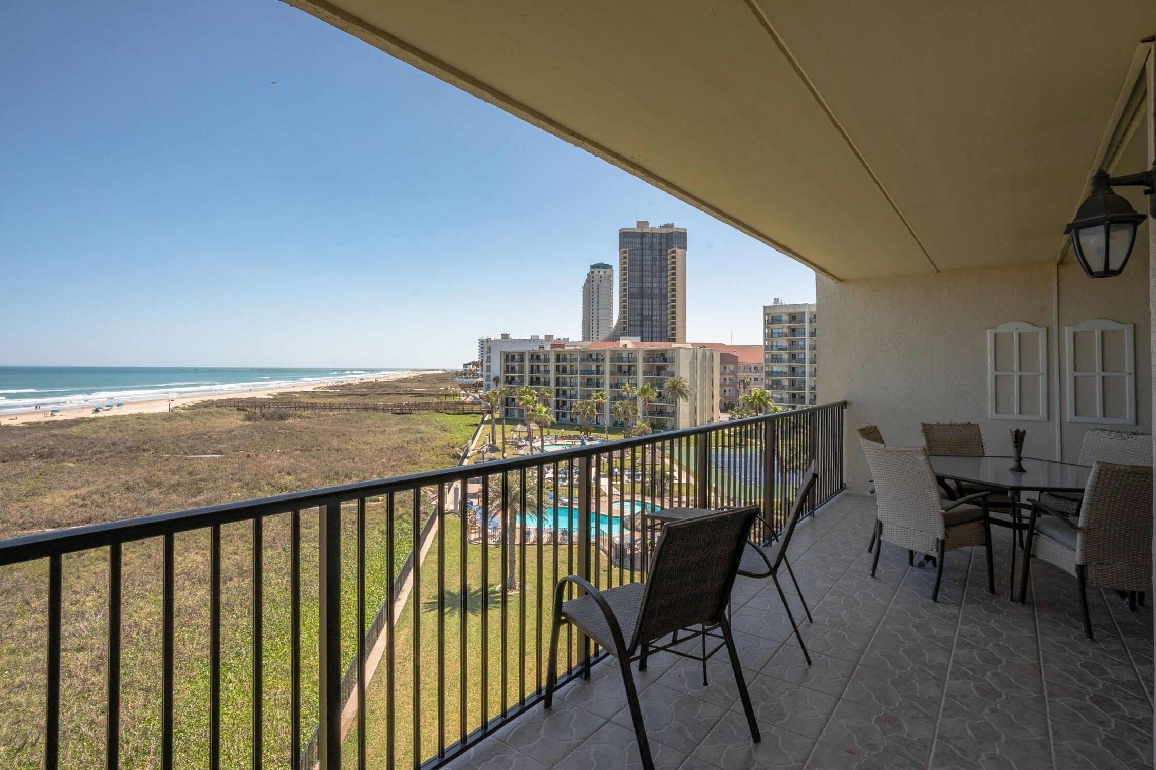 Un balcon avec vue sur la plage, la piscine et les immeubles de grande hauteur.