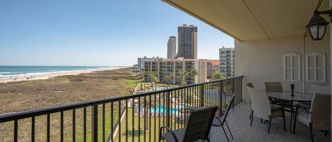 Un balcon avec vue sur la plage, la piscine et les immeubles de grande hauteur.