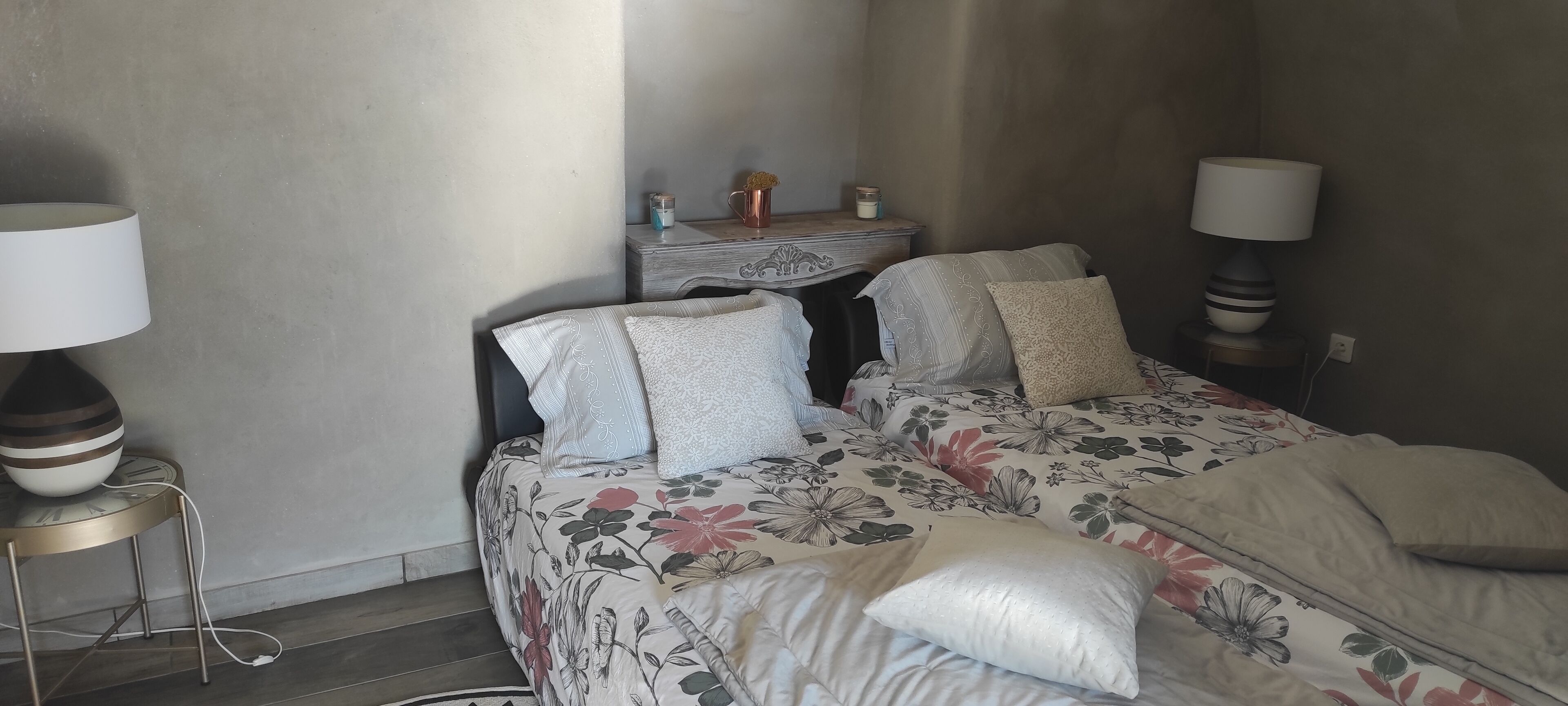 Ein Schlafzimmer mit einem Bett, zwei Nachttischen, einer Lampe und einem Beistelltisch.
