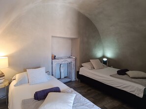 A cozy bedroom with two beds, a dresser, and a lamp.