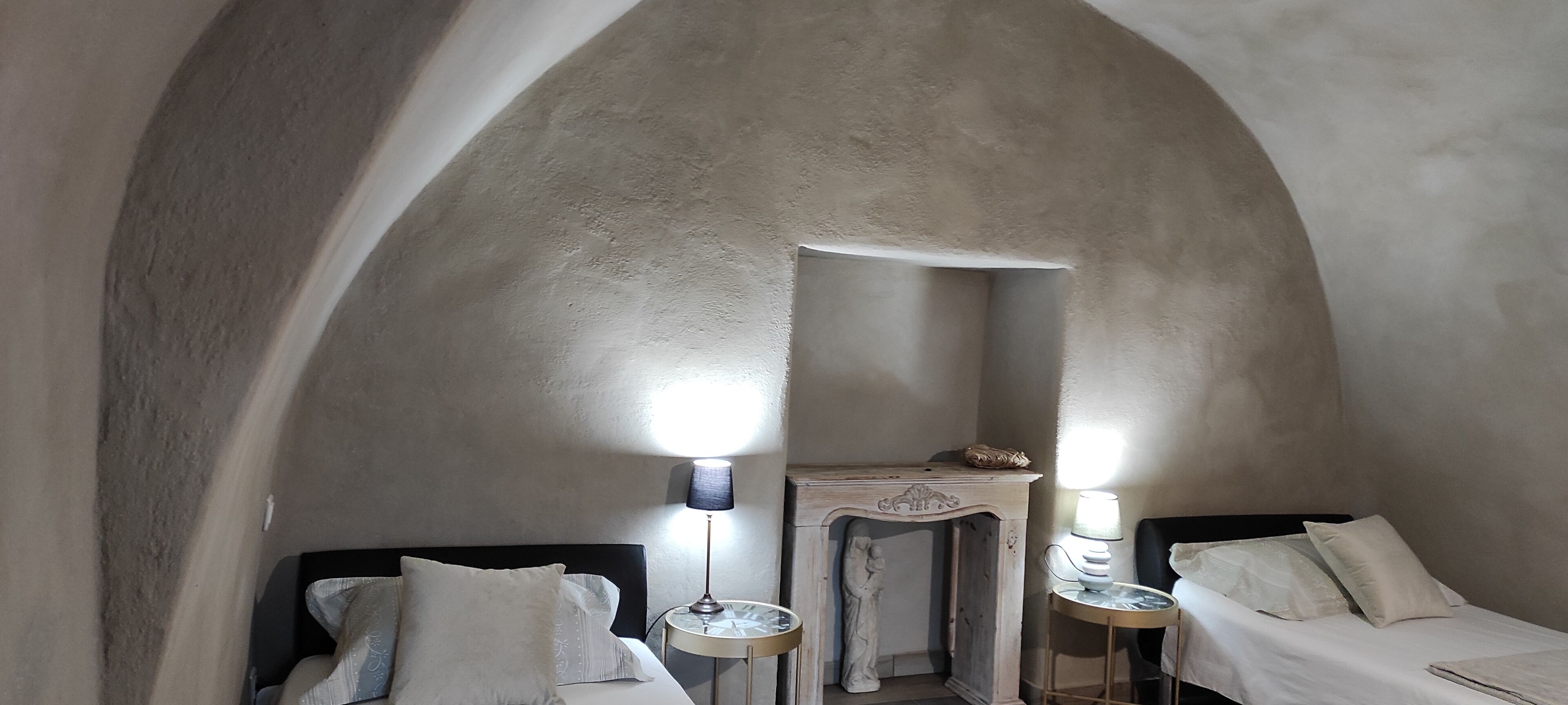 Een kamer met twee bedden, een klein tafeltje met een lamp en een beeld in de hoek.