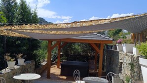 Eine Außenpatio-Terrasse mit einer Pergola, Steinmauern und Kübelpflanzen.