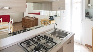 Une cuisine moderne équipée d’une cuisinière à gaz, d’un évier, de meubles de rangement en bois et d’une petite table à manger.