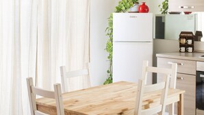 Une cuisine avec une table et des chaises en bois, un réfrigérateur et une machine à café.
