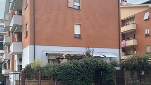 Un immeuble résidentiel à plusieurs étages, doté d’une façade en briques, de balcons et d’une entrée sécurisée par un portail.