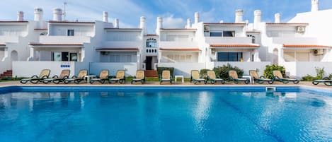 Una piscina al aire libre, tumbonas