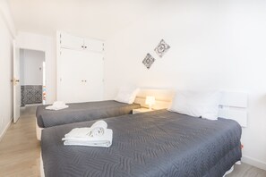 A hotel room with two beds, a white wardrobe, and a patterned wall decoration.