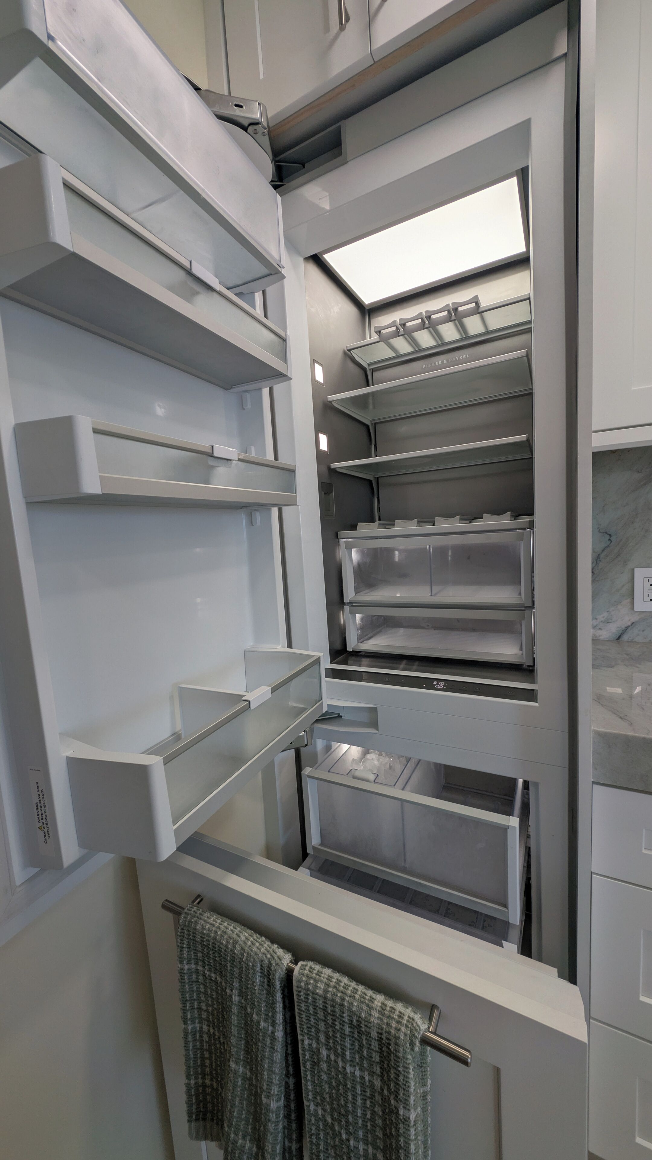A modern kitchen with stainless steel appliances, multiple storage drawers, and a built-in oven.