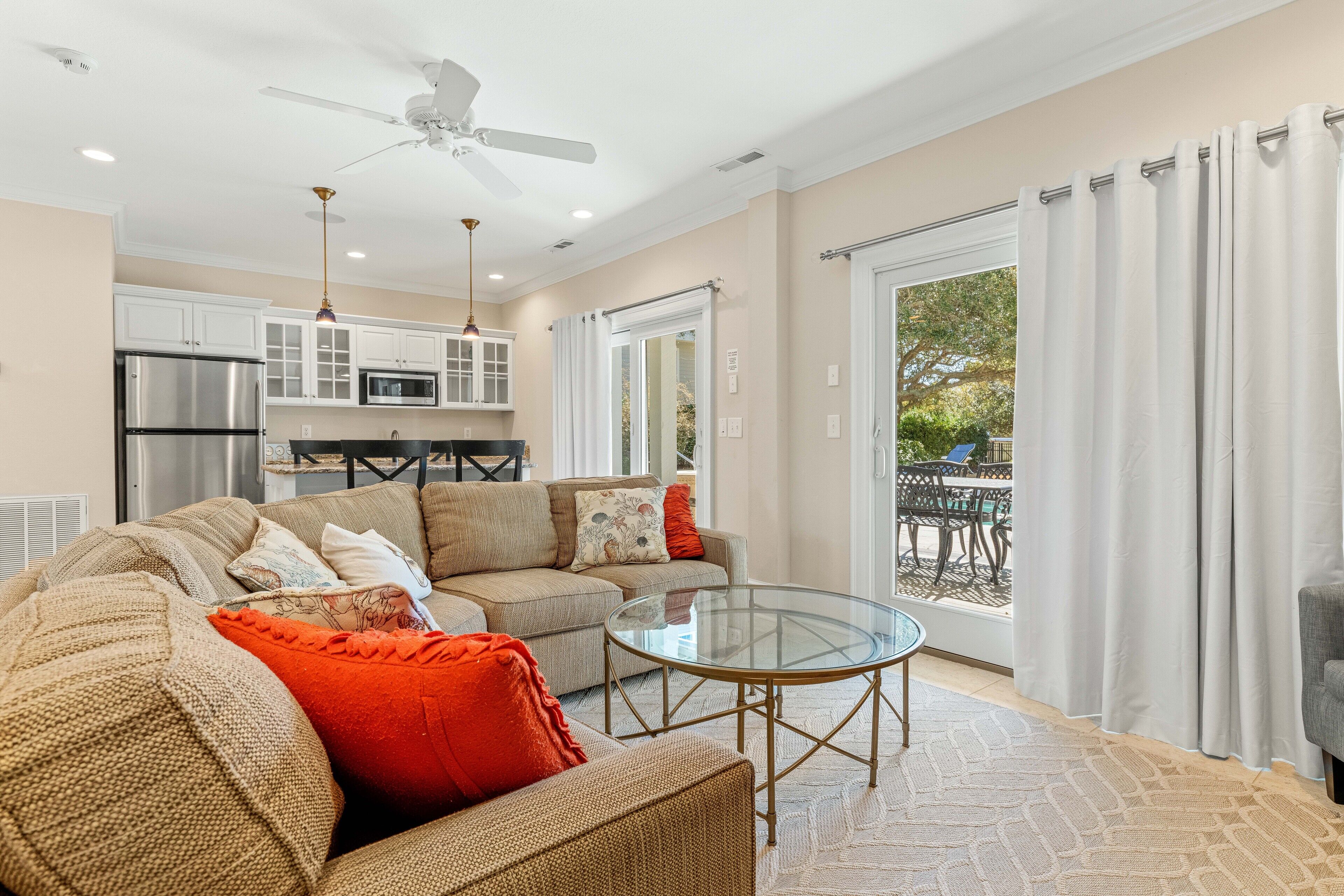 A spacious living room with a sofa, a glass coffee table, and a ceiling fan.