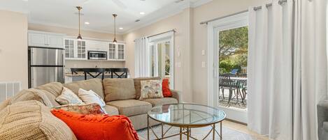 A spacious living room with a sofa, a glass coffee table, and a ceiling fan.