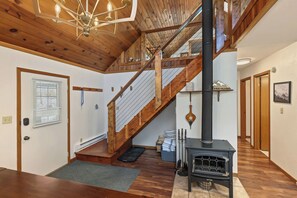 A wooden interior with a staircase, a fireplace, and a dining area. - Aspen Acre – Hot tub, wraparound deck, fireplaces & modern mountain charm! (Lead)