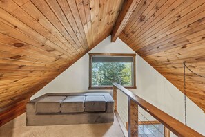 A loft bedroom with a sloped ceiling, a window, and a built-in bench.
