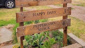 Une pancarte en bois indiquant les différents types d’hébergements Brownlow, avec des sections consacrées à « Island Rest », « Island Time », « Happy Days » et « Peppercorn Shack ».