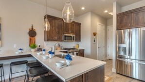 A modern kitchen with a central island, stainless steel appliances, and wooden cabinets. - Oasis at Ocotillo 48, Private Pool and Spa! Ping Pong table, Nintendo Switch & Resort pool (Santa Clara)