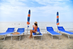 On the beach, white sand, sun-loungers, beach towels