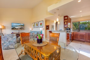 A modern kitchen with wooden cabinets and a glass dining table.