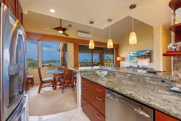 Una cocina moderna con una isla grande, electrodomésticos de acero inoxidable y vistas al océano.