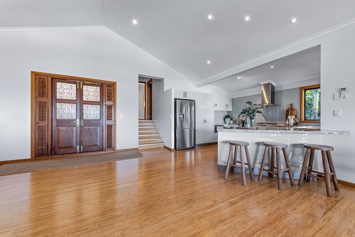 A modern kitchen with a central island, stainless steel appliances, and wooden stools.