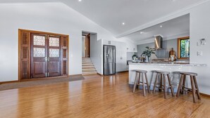 Cozinha moderna com ilha central, eletrodomésticos de aço inoxidável e banquetas de madeira.