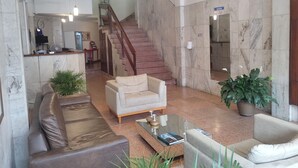A spacious lobby with a marble floor, a staircase, leather sofas, and a reception desk. - Mônaco Hotel (Juiz de Fora)