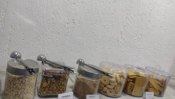 Ein Regal mit beschrifteten Behältern voller Granola, Schokolade, Biscotti und Kekse.