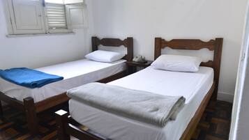 Two single beds with wooden frames, white linens, and a small bedside table with a telephone.
