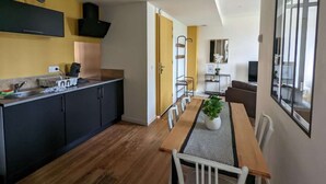 Eine moderne Küche mit dunklen Schränken, einem Holztisch und Blick zum Wohnbereich.