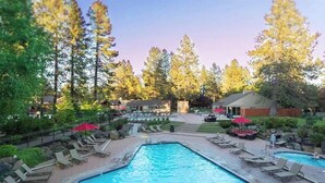 A swimming pool with lounge chairs and umbrellas, surrounded by trees and buildings. - Amazing Resort - Pools, Hot Tub, Hiking, 10 min to Bend and Bachelor (Bend)