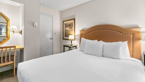 A hotel room with a large bed, a wooden headboard, a desk with a chair, a mirror, and a painting on the wall. - Amazing Resort - Pools, Hot Tub, Hiking, 10 min to Bend and Bachelor (Bend)