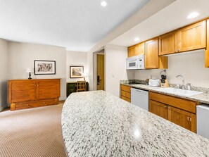 A kitchen with granite countertops, wooden cabinets, a microwave, and a dishwasher.