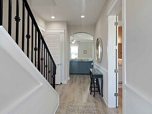 A hallway with a staircase, a dining area with a blue sofa, and a large mirror on the wall. - Sunshine Vacation Home | 4 Bikes, Golf Cart for extra fee (Miramar Beach)