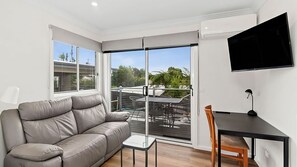 Relax in this stylish living space with a comfortable sofa, flat-screen TV, and sliding glass doors leading to a balcony with a view.