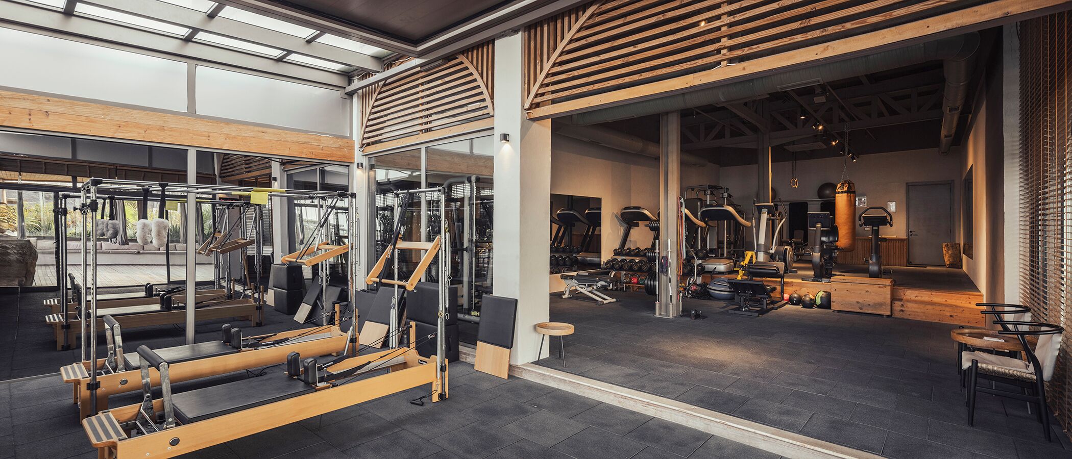 Een fitnessruimte met Pilates apparatuur, gewicht machines en een houten vloer.
