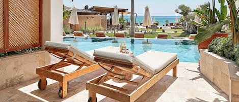 A poolside area with lounge chairs, a wooden cart, and a view of the ocean.