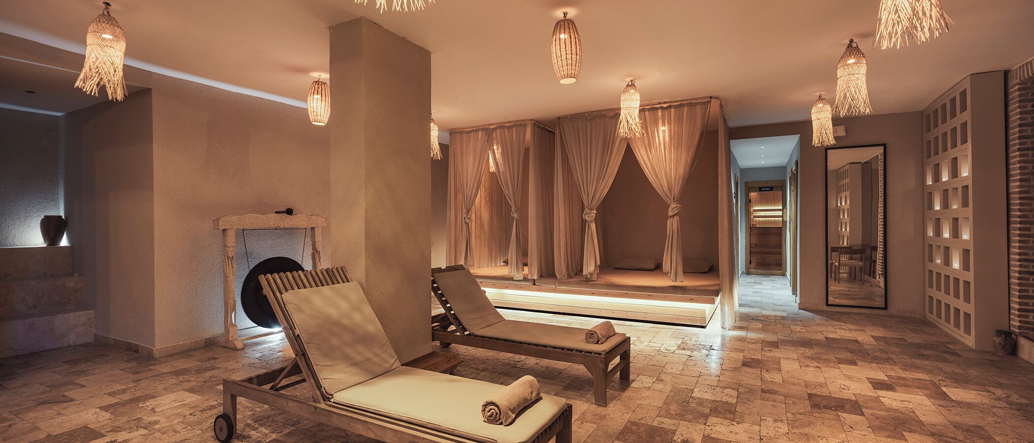 A spa room with two sun loungers, a fireplace, and a mirror.