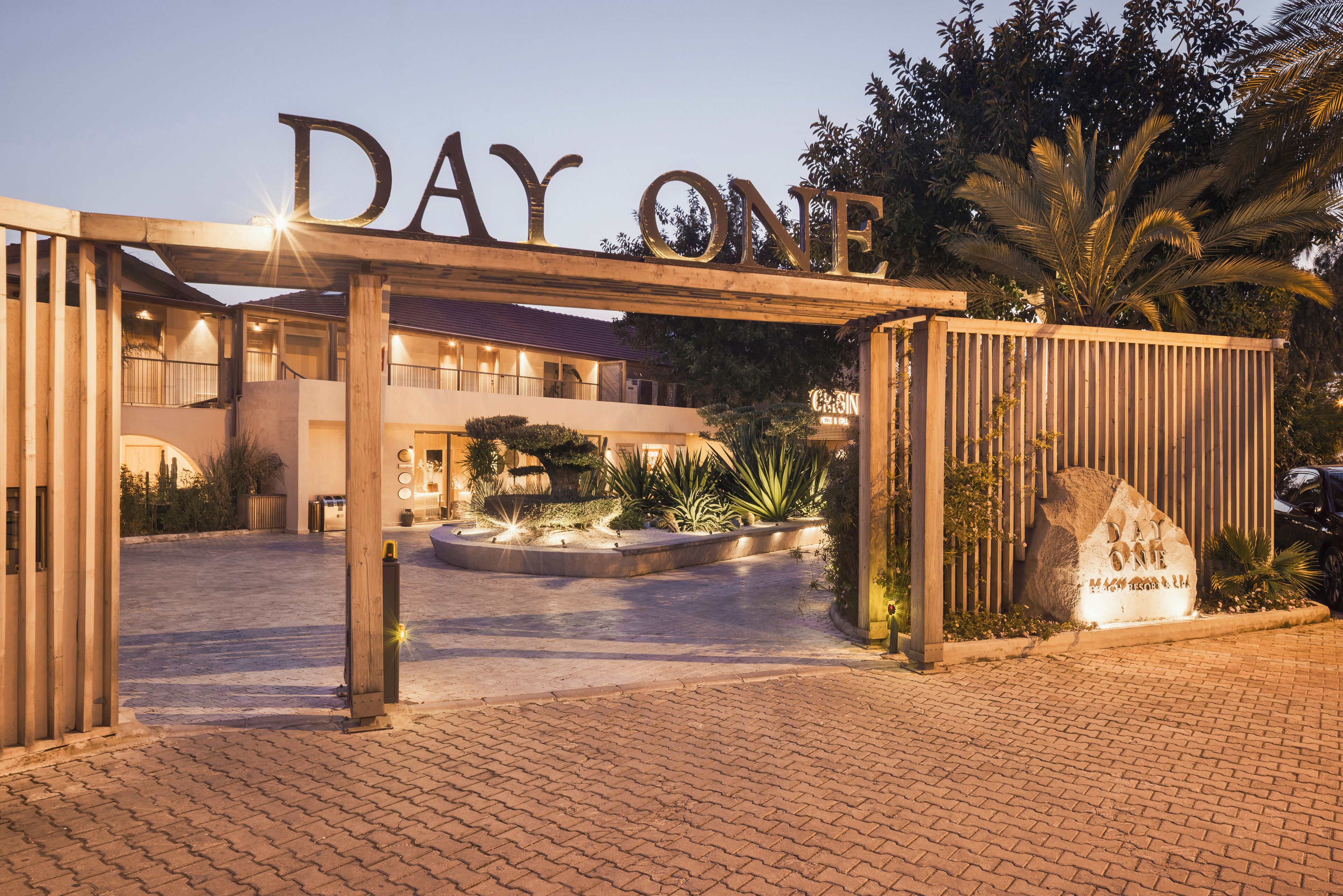 A hotel entrance with a sign reading "DAY ONE" and a large stone with "DAY ONE" engraved.