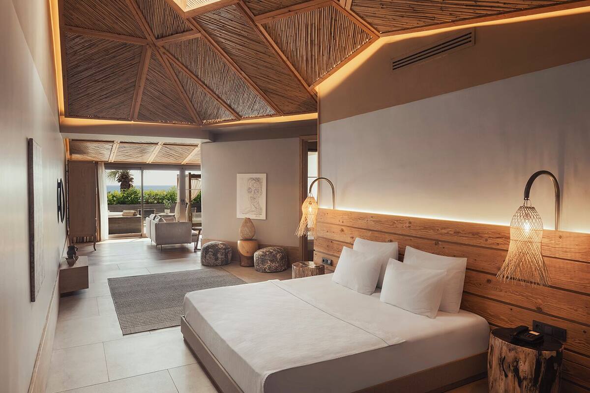 Une chambre à coucher moderne avec un grand lit, un plafond en bois et une vue sur l’extérieur.