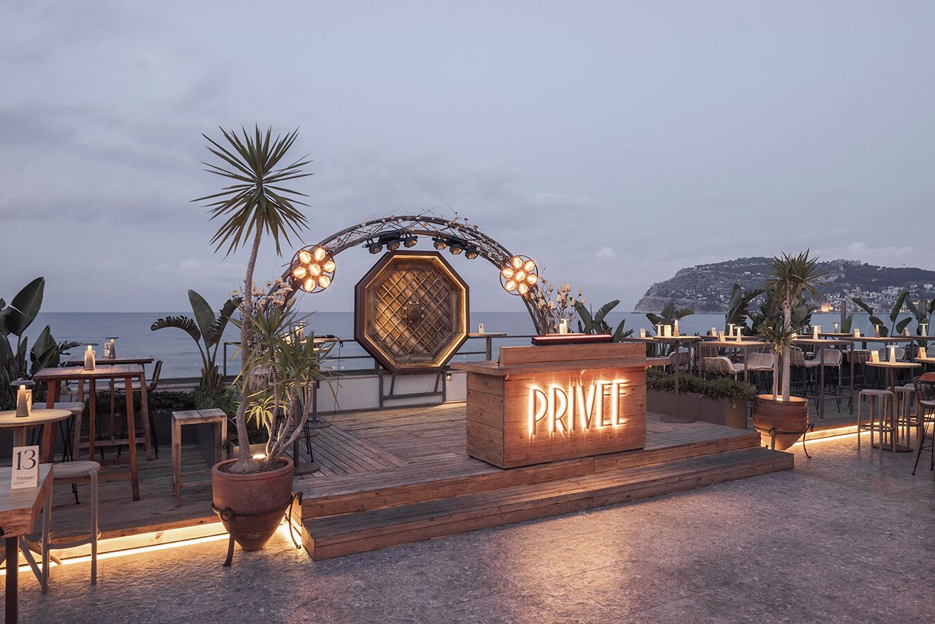 A wooden outdoor seating area with a sign reading "PRIVEE" and a decorative archway.