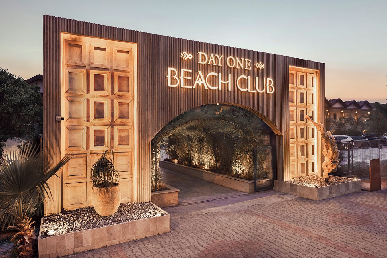 The entrance of Day One Beach Club with a large wooden archway and illuminated signage.