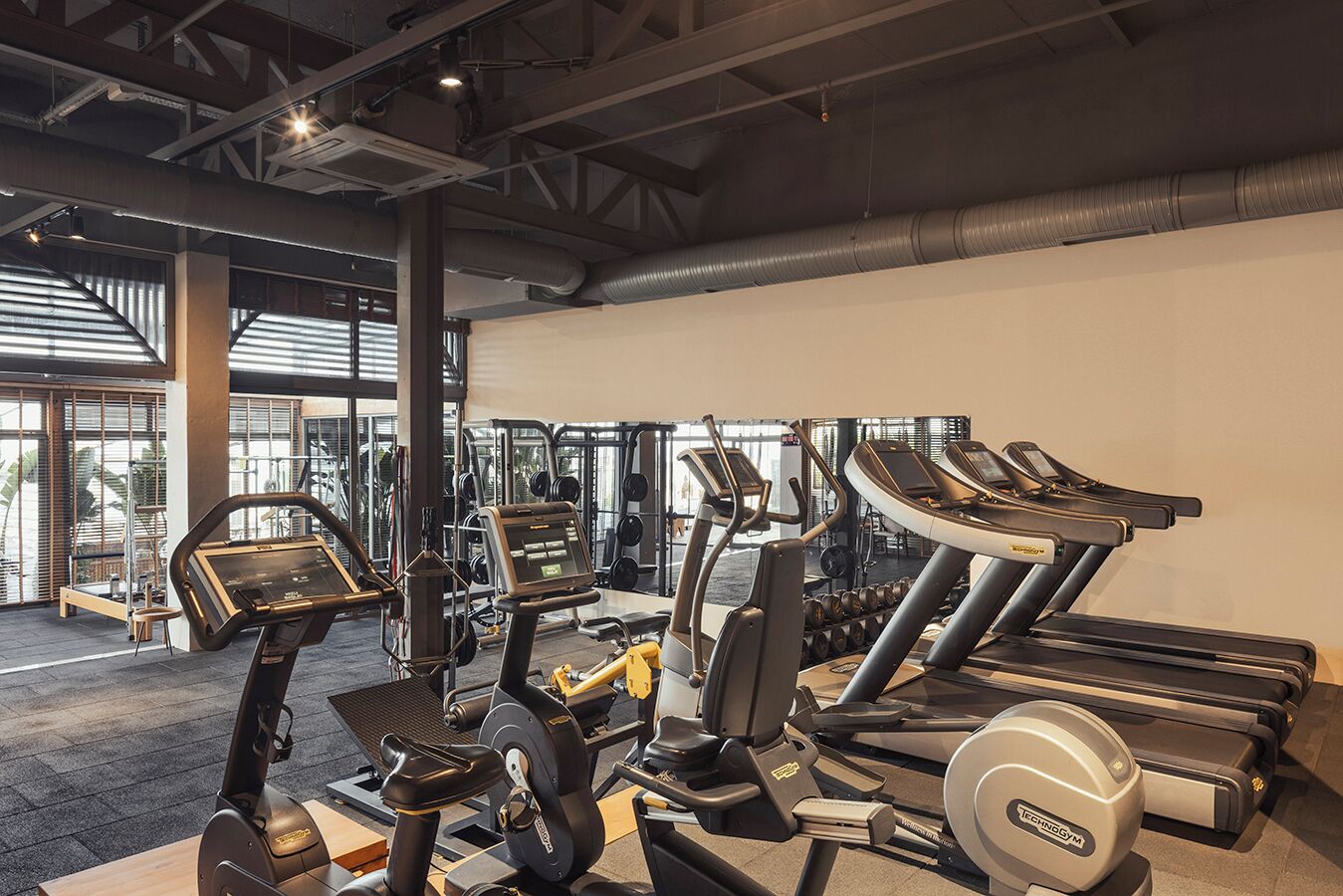 A gym with treadmills, elliptical machines, and weight stations.