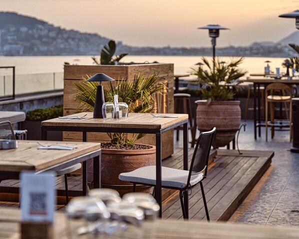 An outdoor dining area with tables, chairs, and potted plants. - Day One Beach Resort & Spa - Adults Only (Alanya)