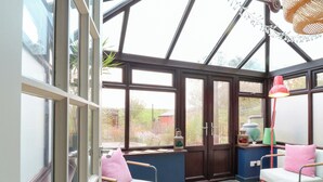 A conservatory with two chairs, a table, and a lamp.