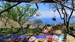 Une terrasse avec une table dressée pour un repas, offrant une vue panoramique sur la côte.